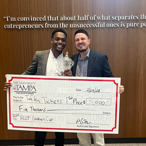 Happyson Kaunda '24 with Justin Heacock posing with a large check